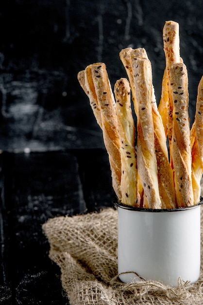 Grissini buonissimi. antipasti italiani. sfondo scuro in legno e tela in tazza di metallo vecchio stile.