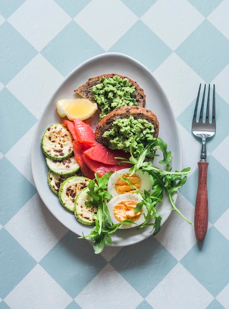 Delicious breakfast boiled egg smoked salmon grilled zucchini avocado sandwich on a light background top view