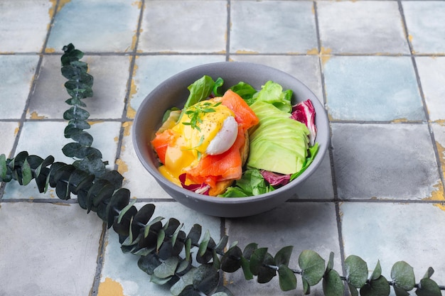 Delicious breakfast brunch  poached egg salmon avocado arugula salad on a tile background high quali...