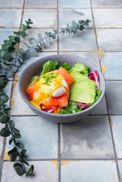 Delicious breakfast brunch  poached egg salmon avocado arugula salad on a tile background high quali...