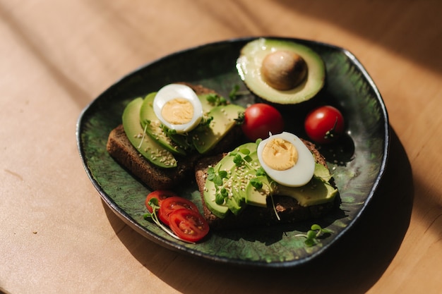 Delicious breakfast at home. Sandwich with fresh sliced avocado above rye toasted bread with cherry