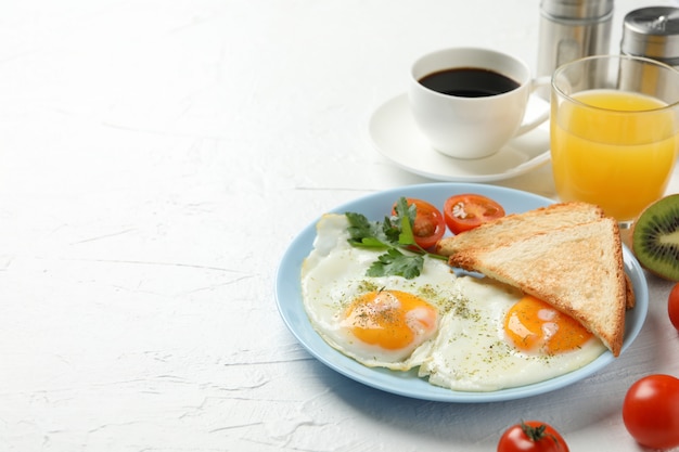 Delicious breakfast or lunch with fried eggs on white table, space for text