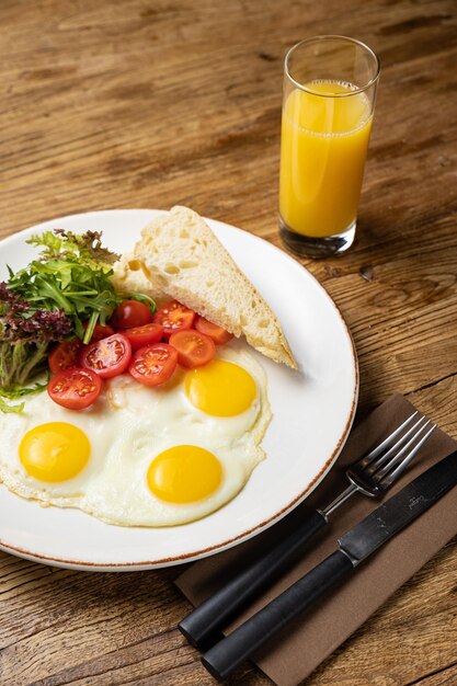레스토랑에서 준비된 접시에 담긴 맛있는 아침 식사. 토마토와 샐러드를 곁들인 튀긴 계란