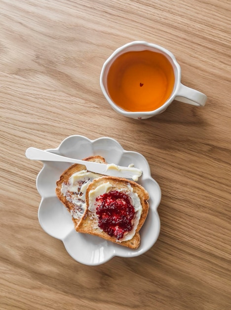 Delicious breakfast toasts with butter and cranberry jam on a wooden background top view