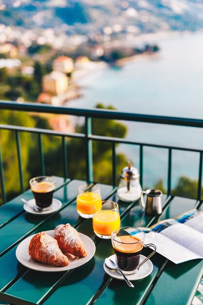 Delicious breakfast with coffee pastry and orange juice served on the balcony with sea view in Italy