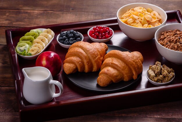 Foto deliziosa colazione con cornetti freschi e bacche mature su un bellissimo tavolo di legno