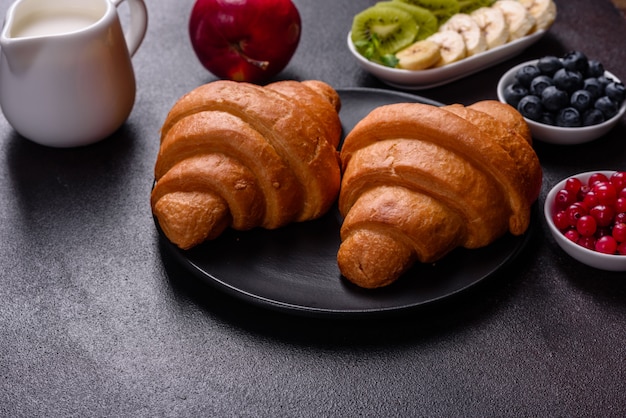 Delicious breakfast with fresh croissants and ripe berries on a beautiful wooden table