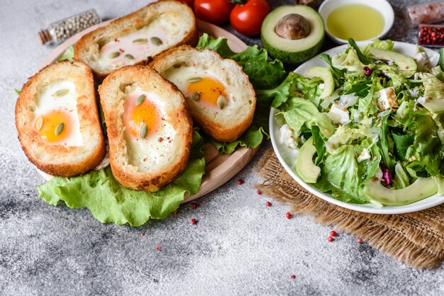 신음 소리, 계란, 아보카도, 체리 토마토와 함께 맛있는 아침 식사. 신선한 샌드위치와 함께 즐거운 아침 식사