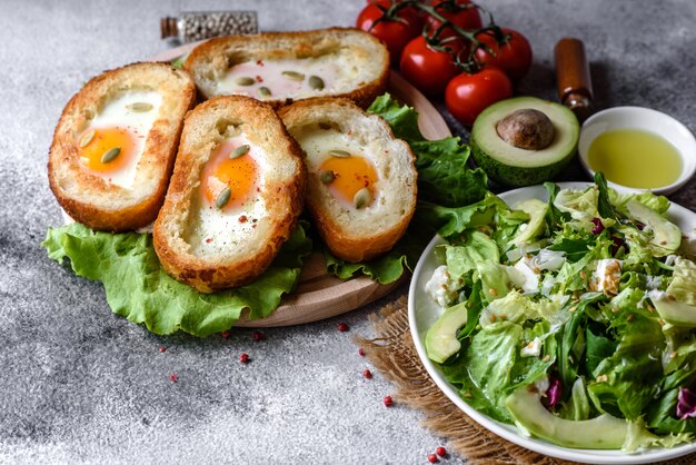 신음 소리, 계란, 아보카도, 체리 토마토와 함께 맛있는 아침 식사. 신선한 샌드위치와 함께 즐거운 아침 식사