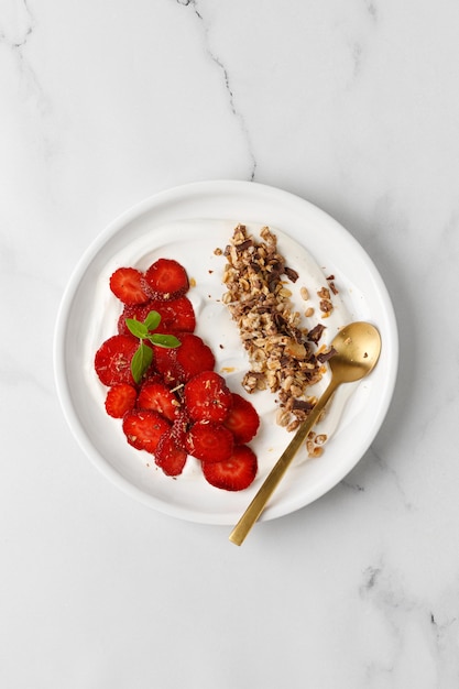 Delicious Breakfast with Yogurt strawberry and granola in white plate Creamy dairy product Top view marble background