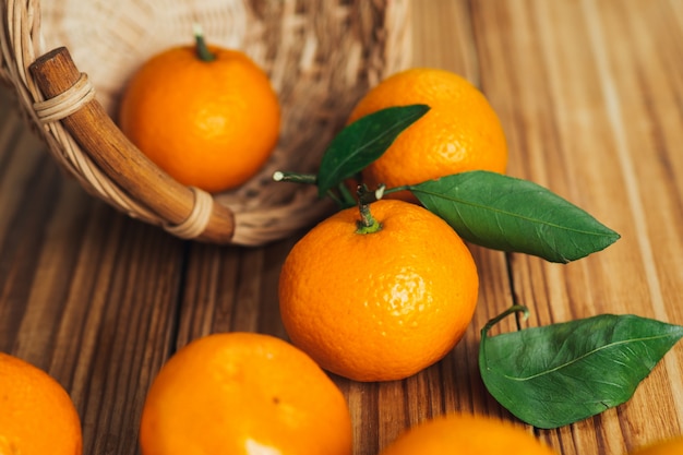 Delicious bright ripe tangerines with leaves on a wooden table