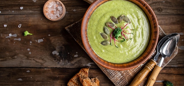 Delicious broccoli cream soup served with microgreen pumpkin seeds on a rustic table Vegetarian dish banner catering menu recipe place for text top view