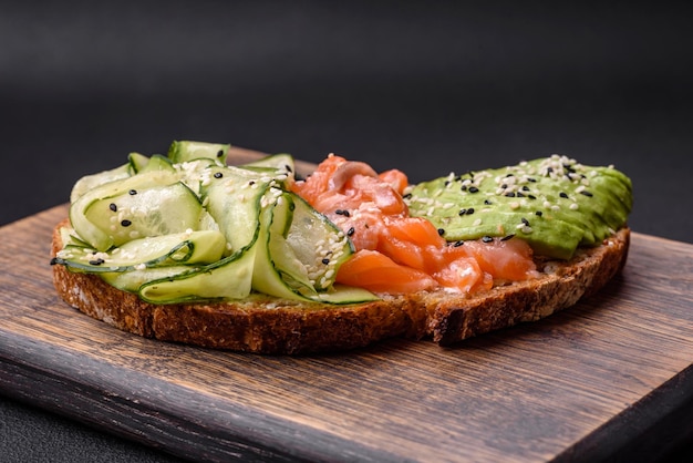 Delicious brown bread toast with salmon avocado cucumber and sesame seeds