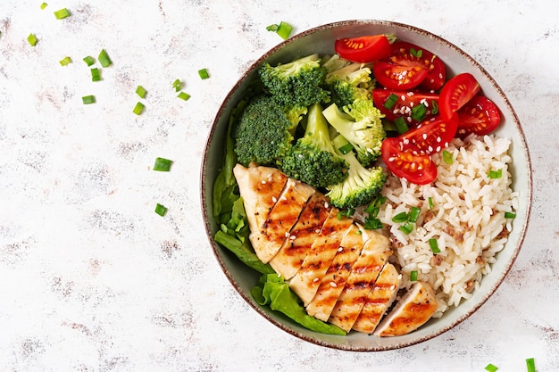 Photo delicious buddha bowl with grilled chicken fresh vegetables and rice on a light background top view above