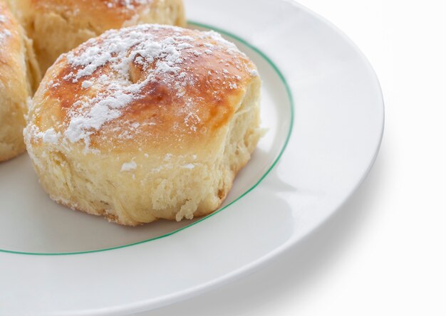 Delicious buns with powdered sugar on a white plate