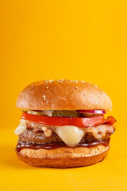 Delicious burger isolated on yellow background. Tasty fresh unhealthy hamburgers with cheese