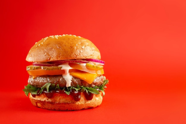 Delicious burger with beef and cheddar cheese on a red background. tasty fresh unhealthy burgers with cheese and two patties. fast food, unhealthy food concept