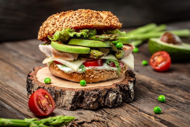 Delicious burger with chicken fillet, asparagus, avocado, tomatoes, peas, cheese and tartar