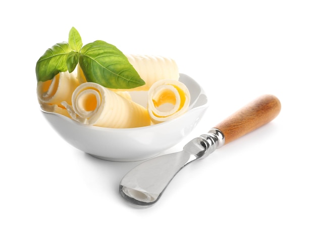 Delicious butter curls with basil leaves in bowl and shovel on white background closeup