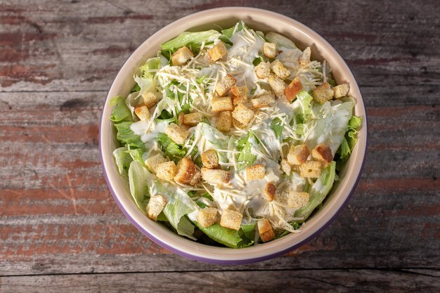 Delicious caesar salad in bowl on wooden background