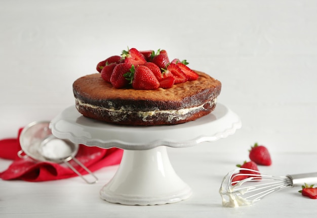 Delicious cake decorated with strawberry on white stand