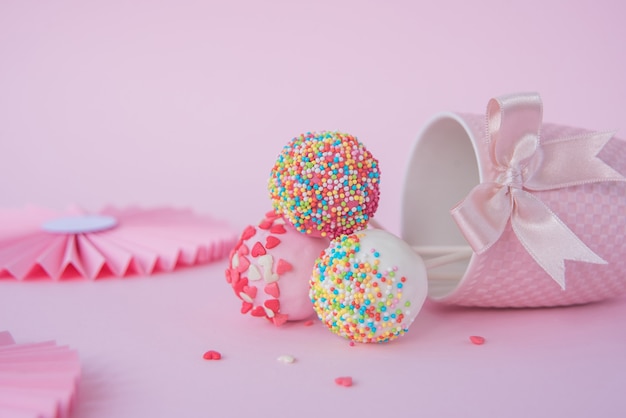 Delicious cake and a gift on a pink background, next to a red and pink ribbon.