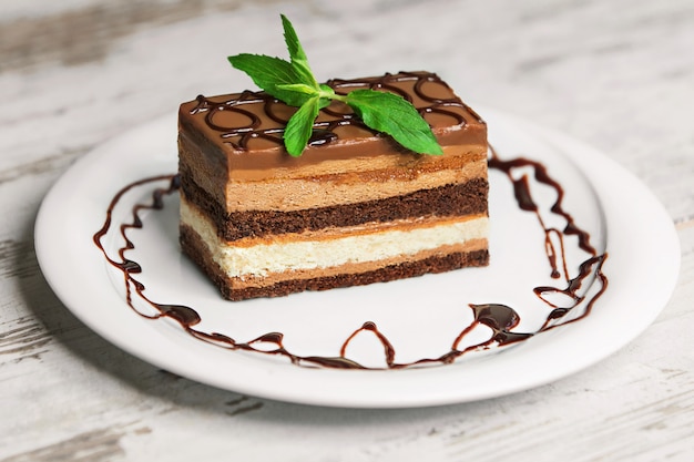 Delicious cake on white plate on wooden table