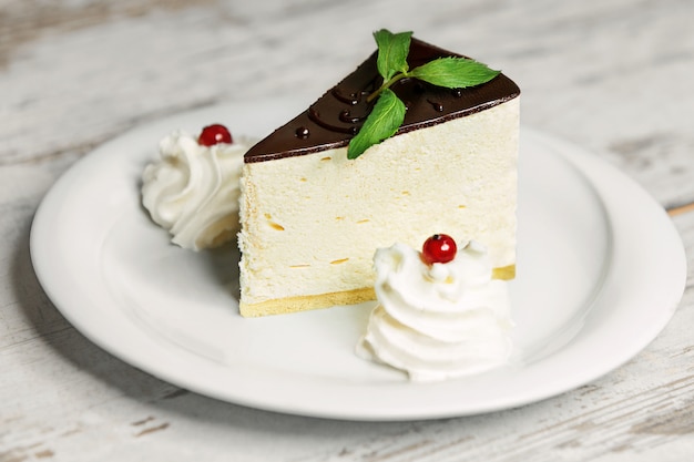 Delicious cake on white plate on wooden table