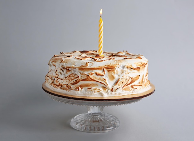 Delicious cake with candle on grey background