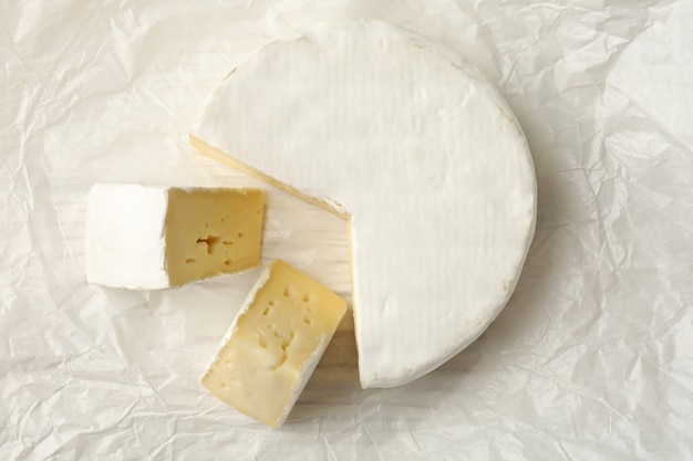 Delicious camembert cheese on paper, top view