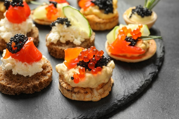 Delicious canapes with black caviar on slate plate closeup