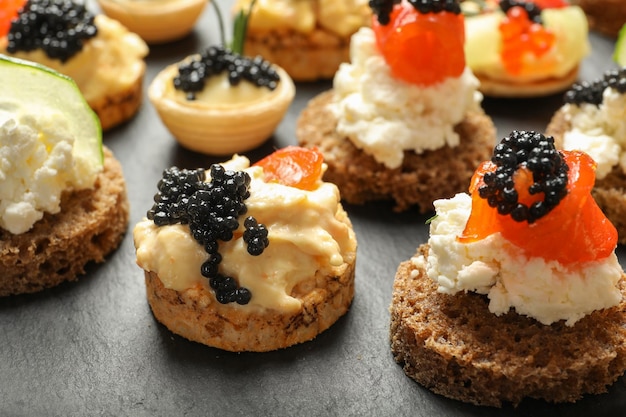 Delicious canapes with black caviar on slate plate closeup