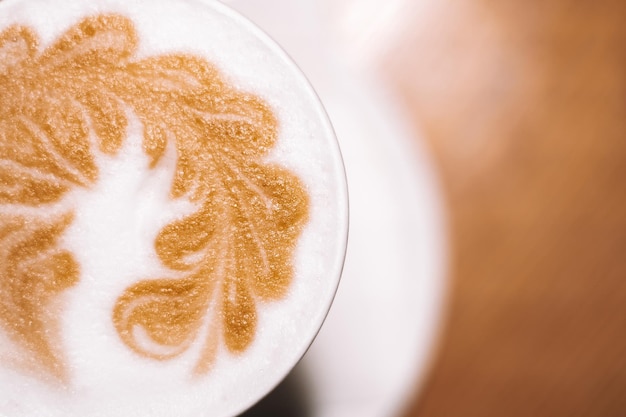 Foto delizioso caffè cappuccino in tazza di latte in vetro con panna acida e schiuma di latte con motivo a punta su piatto in ceramica bianca