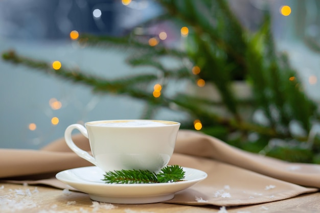 Delicious cappucino coffee cup with fireflies and spruce branches