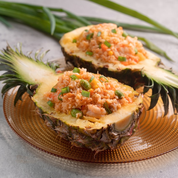 Delicious carved pineapples served as a bowl containers stuffed with fresh pineapple, tomato sauced, seafood and fried rice