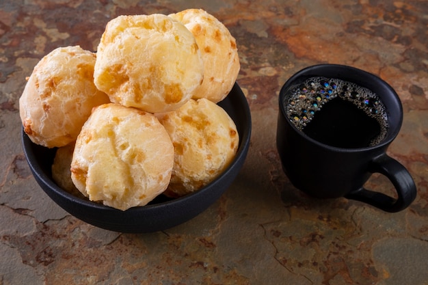 Delicious cheese breads and a cup of coffee on rusty slate