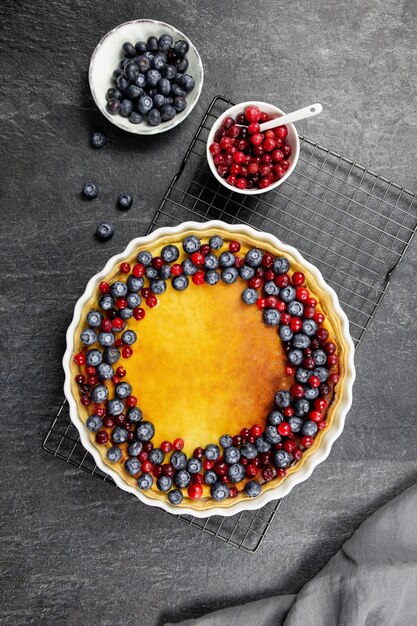 Photo delicious cheesecake tart with fresh blueberries and cranberries on a dark stone surface