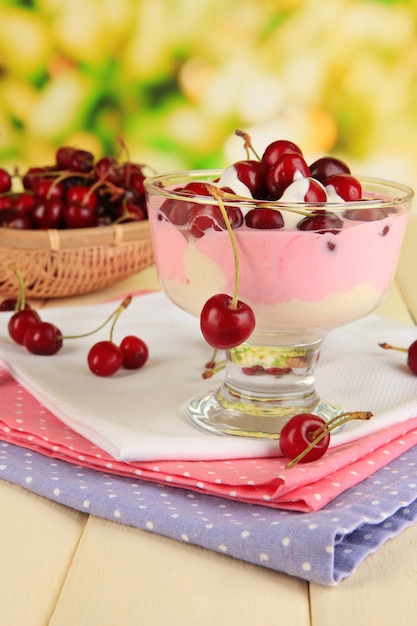 Delicious cherry dessert in glass vase on wooden table on natural background