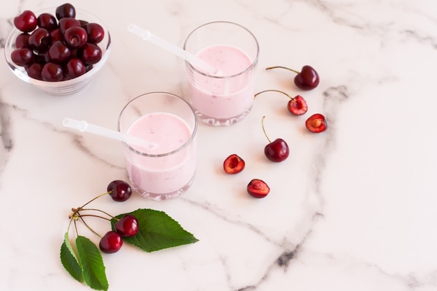 Delicious cherry smoothie in glass glasses on a marble table. bowl with fresh cherries.