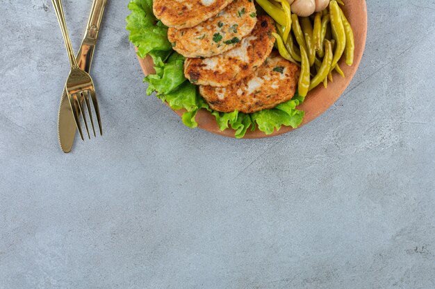 石のテーブルに野菜を載せた美味しいチキンカツレツ。