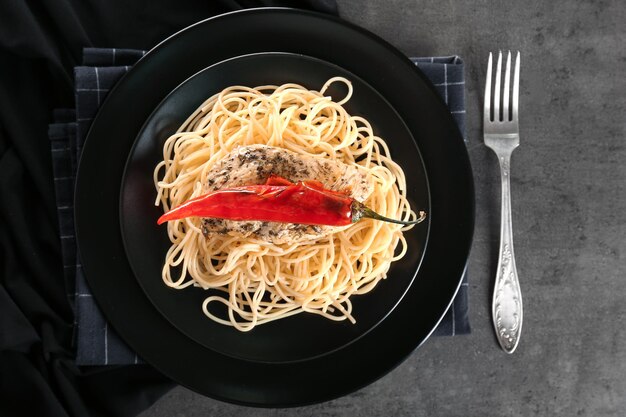 Delicious chicken spaghetti with pepper on black plate