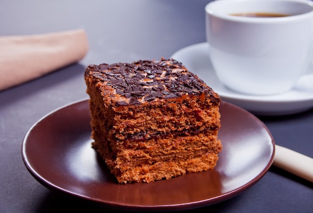 Delicious chocolate cake on the brown platewith cup of coffee on the black table