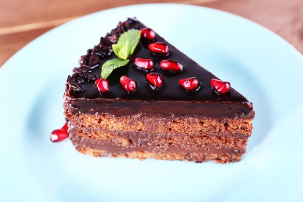 Delicious chocolate cake decorated with pomegranate seeds on plate on table