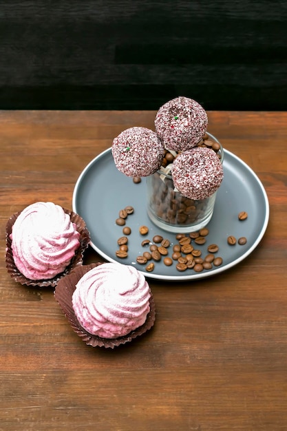 Photo delicious chocolate cake pops decorated white sprinkles on plate in glass with coffee beans, marshmallow on wooden black background, pastry, desserts on stick. tasty food