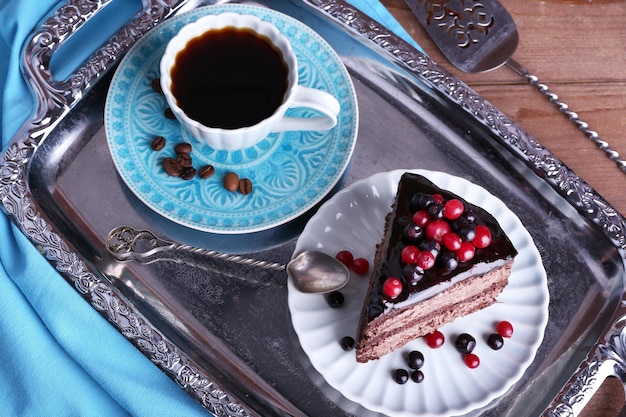 Delicious chocolate cake with berries and cup of coffee on table close up