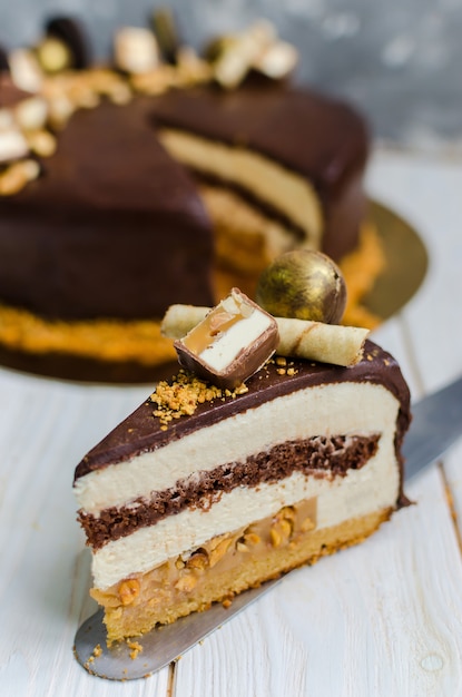 Delicious chocolate cake with biscuit, mousse layers, sweets and peanuts