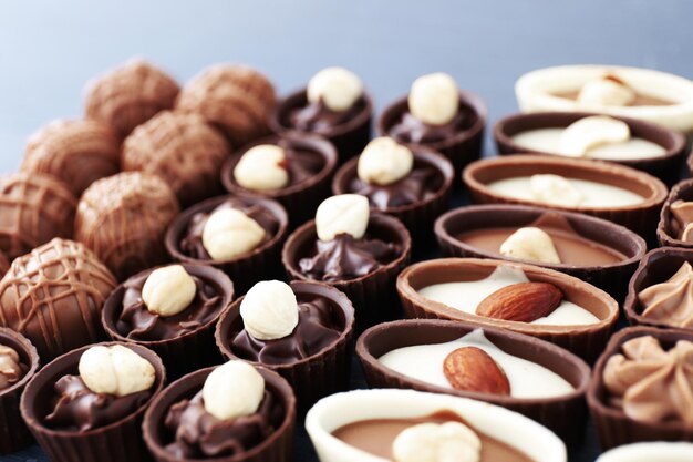 Delicious chocolate candies on blue wooden background, close up