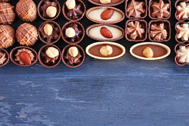 Delicious chocolate candies on blue wooden table