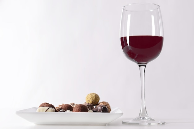 Вкусные шоколадные конфеты и красное вино на белом фоне