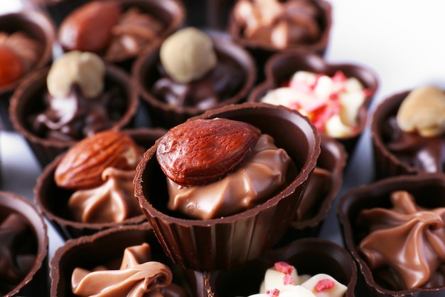 Delicious chocolate candies on white background, close up